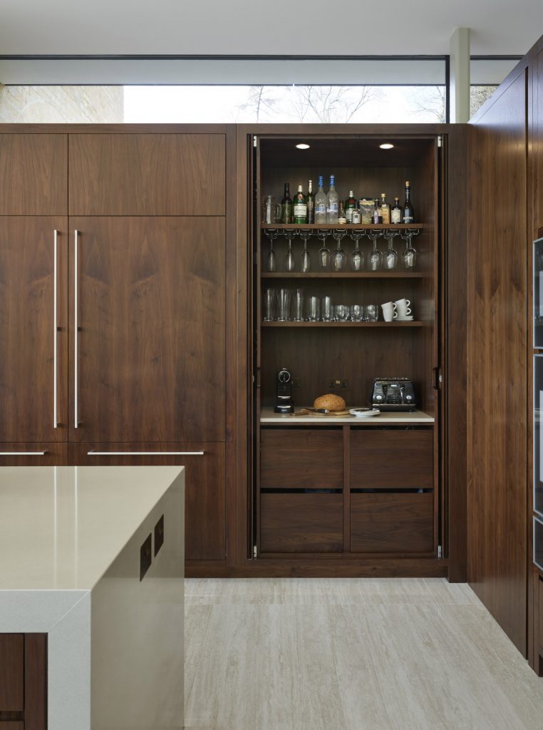 Retractable kitchen cabinet doors open back to reveal breakfast station in Handleless Kitchen by Chamber Furniture