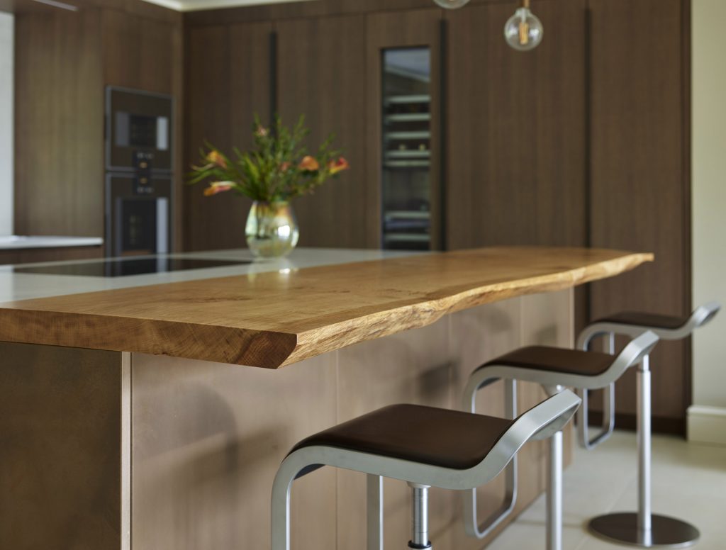 Wooden Kitchen featuring waney edge oak breakfast bar over quartz kitchen countertops by Chamber Furniture