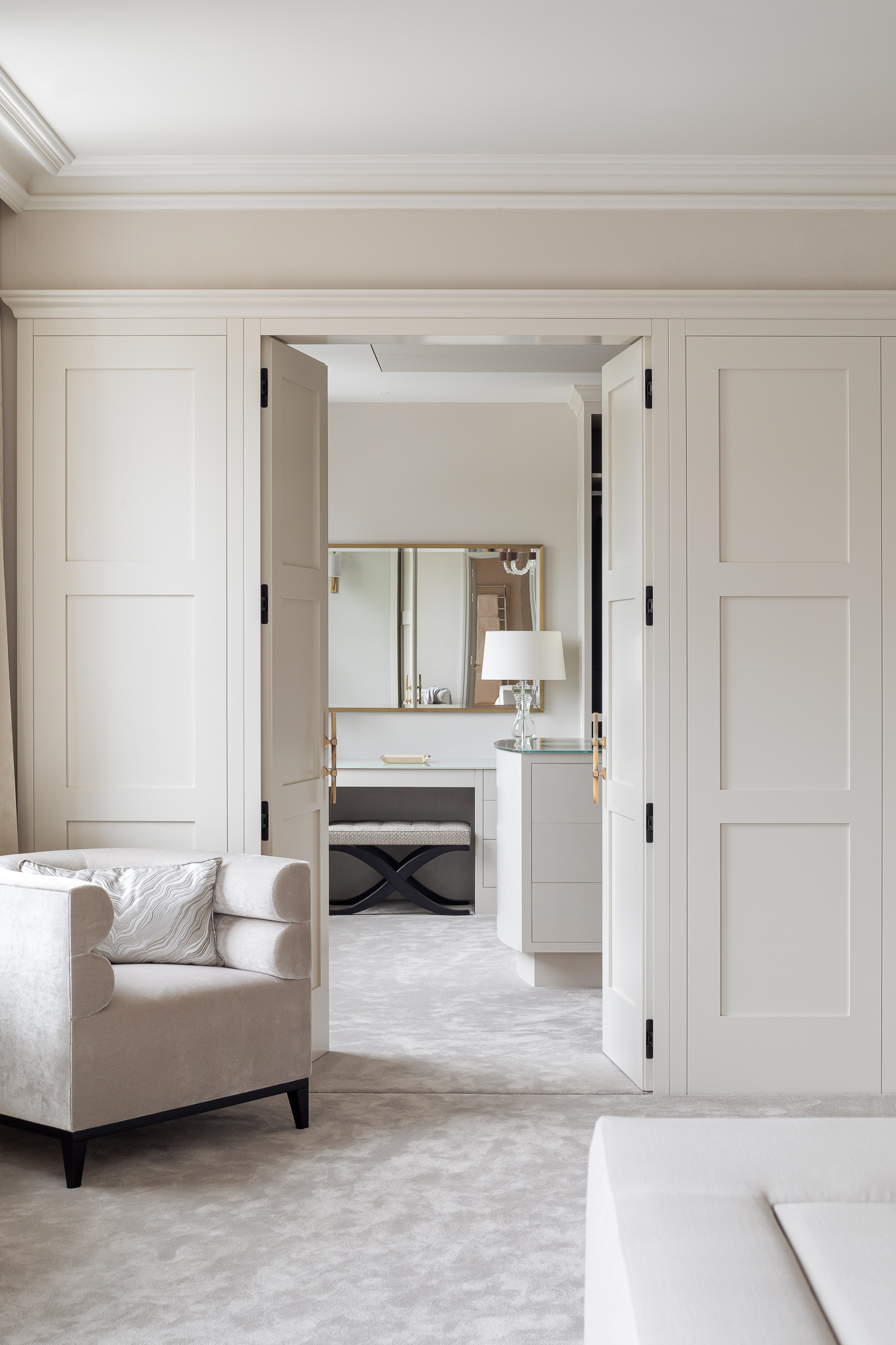 Disguised wardrobe doors in this luxurious bespoke bedroom design lead to the sophisticated dressing room beyond